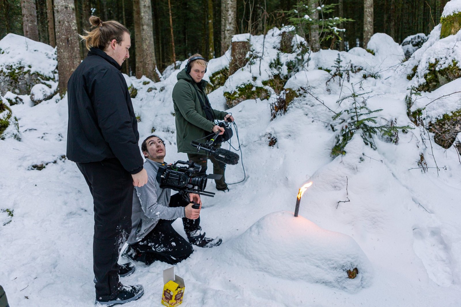 Dreiköpfige Filmcrew mit Kamera und Tonangel bei Dreharbeiten im verschneiten Wald